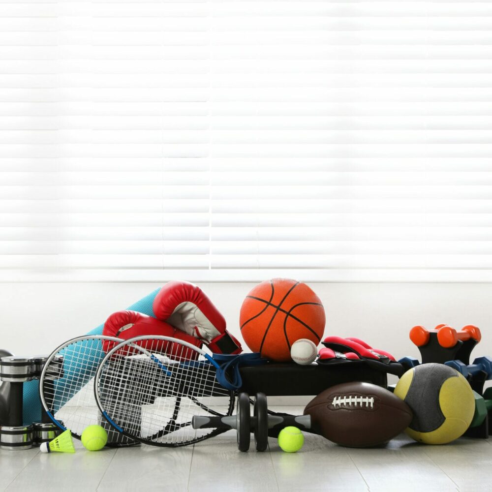 Set of different sports equipment on white floor indoors, space for text